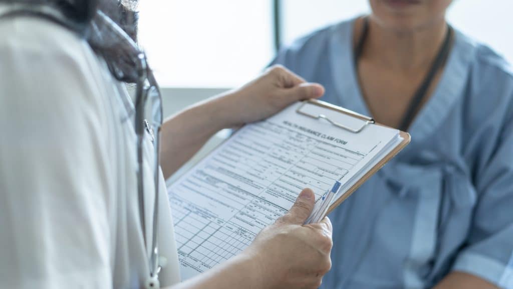 A doctor holding a clipboard and talking to someone.