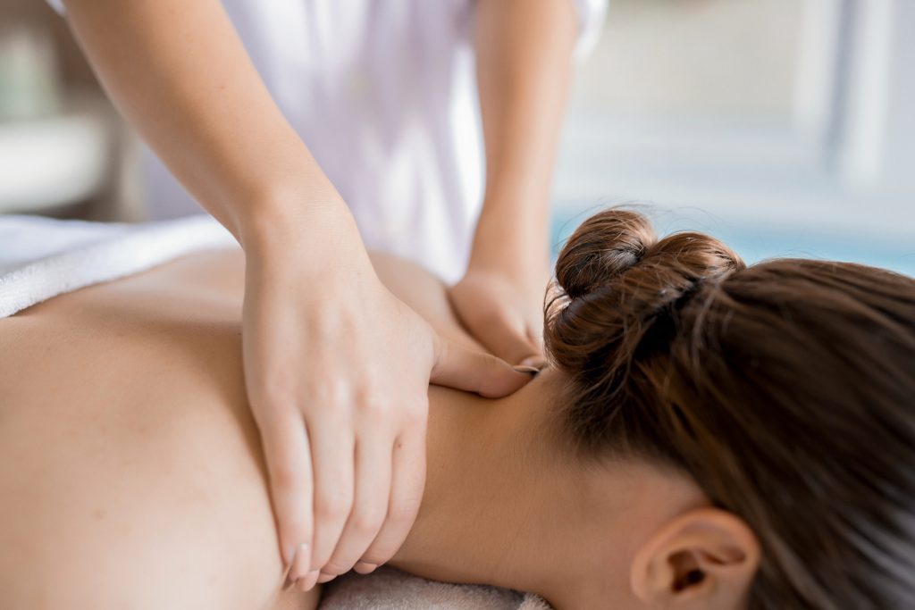 A woman getting her back massage done by a masseuse.