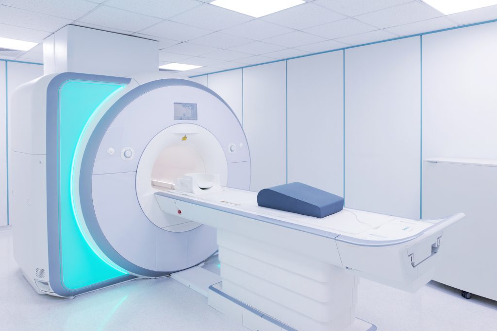 A room with a large white mri machine and a blue chair.